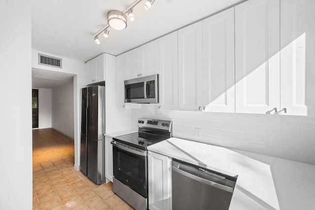 kitchen featuring rail lighting, backsplash, white cabinets, and appliances with stainless steel finishes