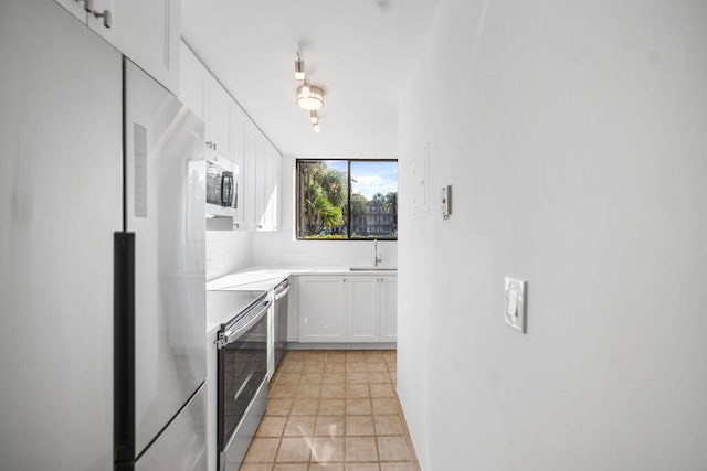 kitchen featuring decorative backsplash, stainless steel appliances, sink, light tile patterned floors, and white cabinets