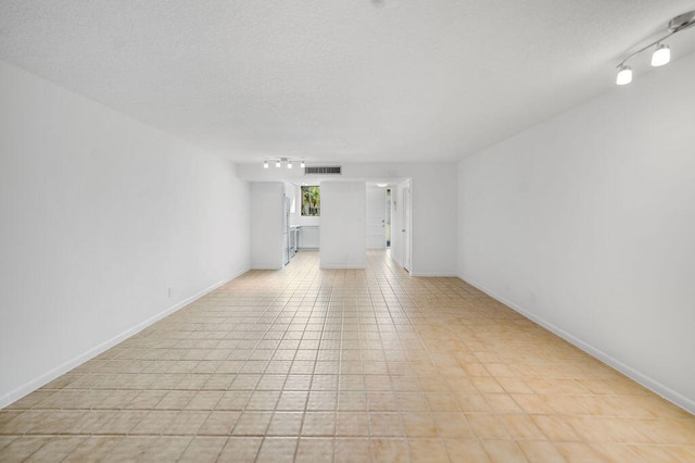 empty room with light tile patterned floors and a textured ceiling