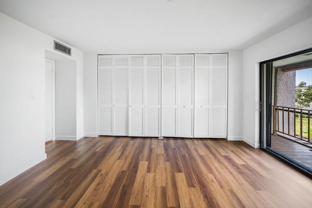 unfurnished bedroom featuring access to exterior and dark hardwood / wood-style floors