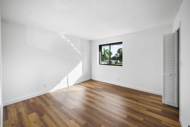 spare room featuring dark hardwood / wood-style flooring and a textured ceiling