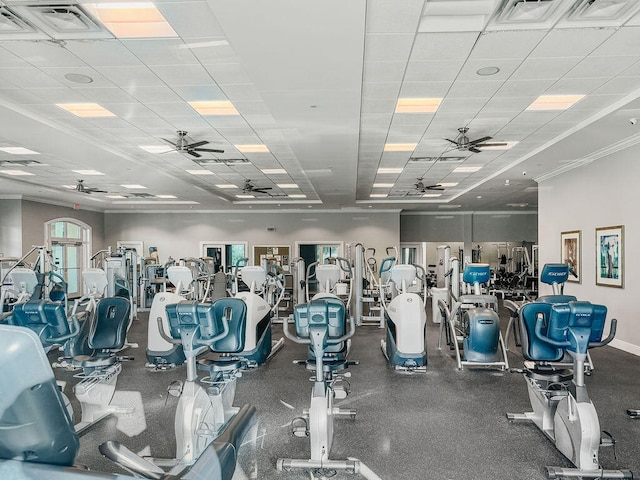 gym with a drop ceiling, ornamental molding, and ceiling fan