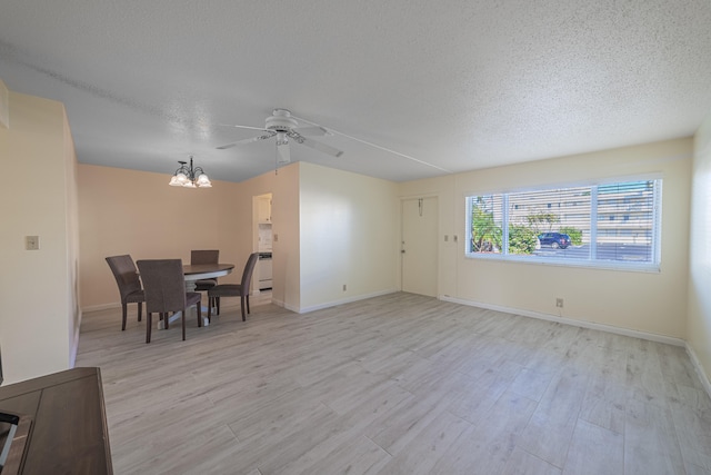 dining space with a textured ceiling, ceiling fan with notable chandelier, and light hardwood / wood-style floors