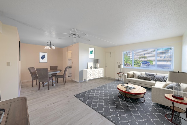 living room with ceiling fan with notable chandelier and light wood-type flooring