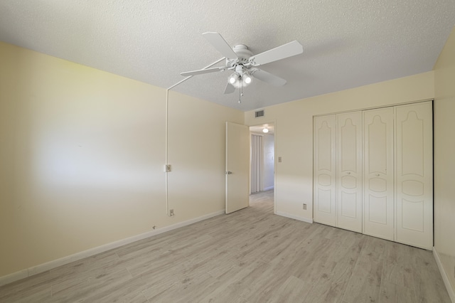 unfurnished bedroom featuring ceiling fan, a closet, a textured ceiling, and light wood-type flooring