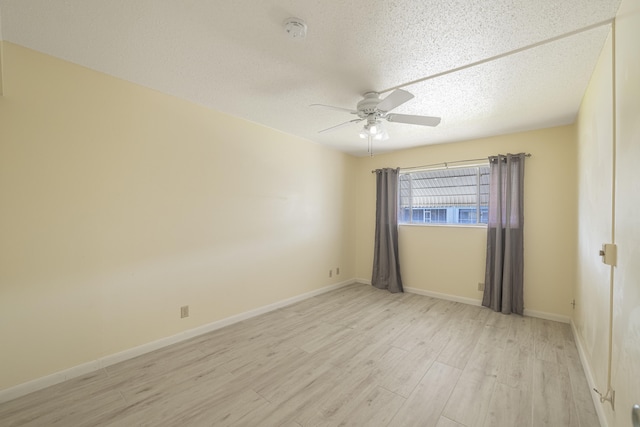 unfurnished room with a textured ceiling, light wood-type flooring, and ceiling fan