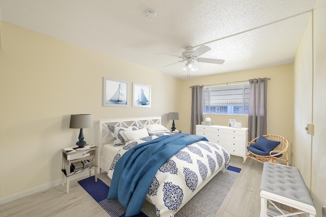 bedroom featuring ceiling fan, a textured ceiling, and light hardwood / wood-style flooring