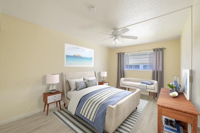 bedroom with ceiling fan, light wood-type flooring, and a textured ceiling