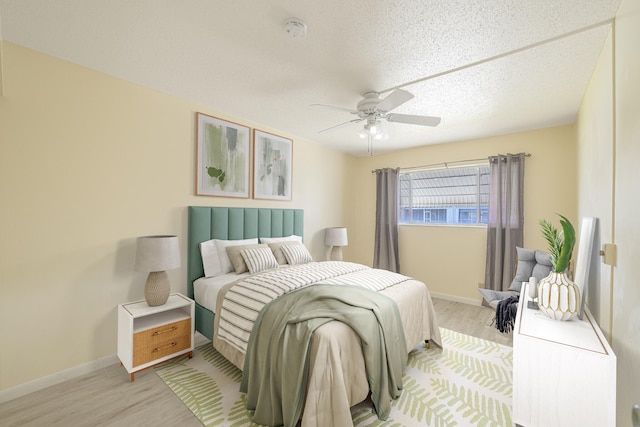 bedroom featuring ceiling fan, light wood-type flooring, and a textured ceiling