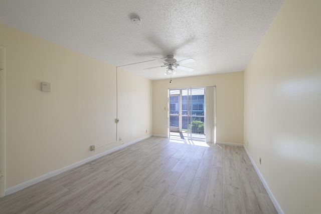 empty room with ceiling fan, light wood-type flooring, and a textured ceiling