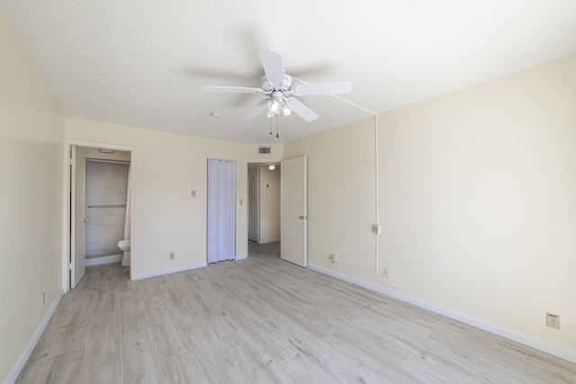 unfurnished bedroom featuring a textured ceiling, ceiling fan, ensuite bathroom, and light hardwood / wood-style flooring