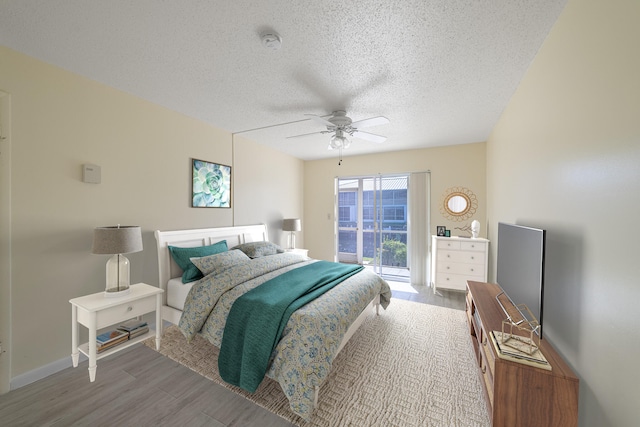 bedroom featuring access to exterior, a textured ceiling, light wood-type flooring, and ceiling fan