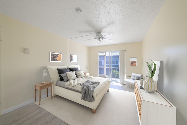 bedroom with access to exterior, a textured ceiling, light hardwood / wood-style flooring, and ceiling fan