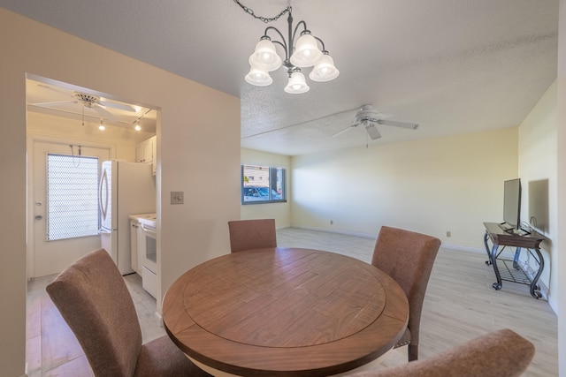 dining area featuring ceiling fan with notable chandelier, a healthy amount of sunlight, light wood-type flooring, and a textured ceiling