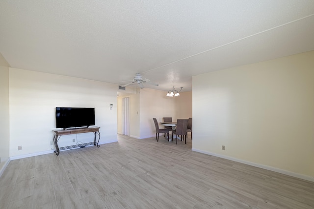 living room featuring ceiling fan with notable chandelier and light hardwood / wood-style flooring