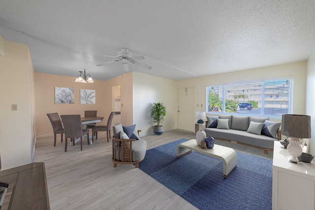 living room featuring a textured ceiling, ceiling fan with notable chandelier, and light hardwood / wood-style floors