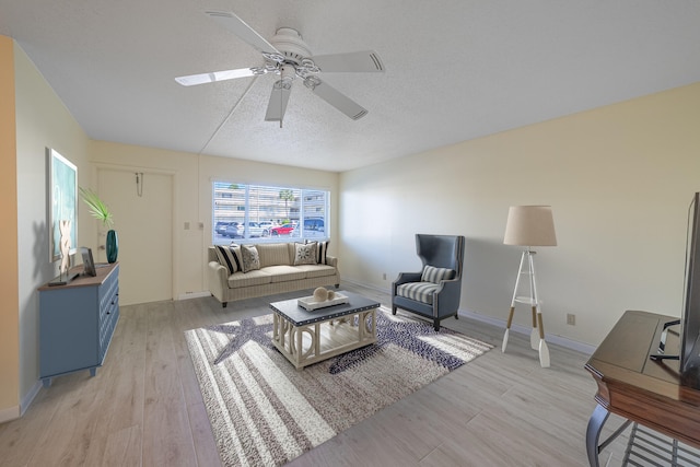 living room with a textured ceiling, light hardwood / wood-style flooring, and ceiling fan