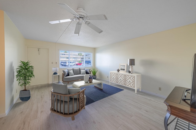 living room with ceiling fan, a textured ceiling, and light wood-type flooring