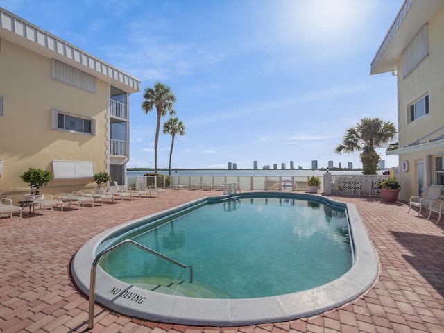 view of pool with a patio area and a water view