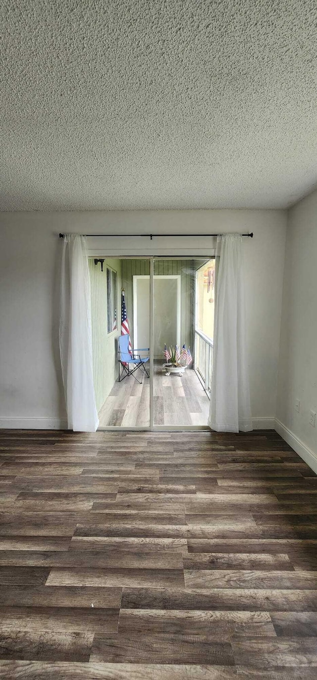 spare room featuring dark wood-type flooring and a textured ceiling