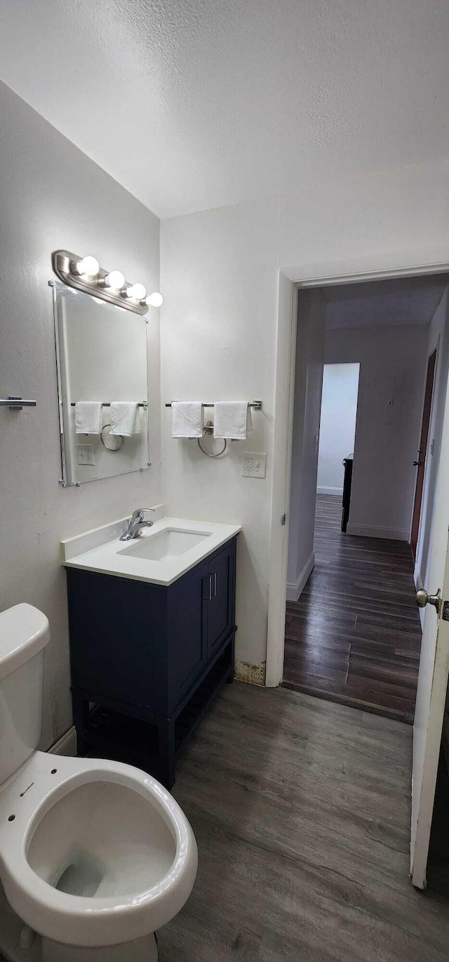 bathroom featuring vanity, toilet, wood-type flooring, and a textured ceiling