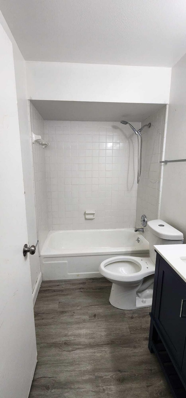 full bathroom with tiled shower / bath, vanity, wood-type flooring, and toilet