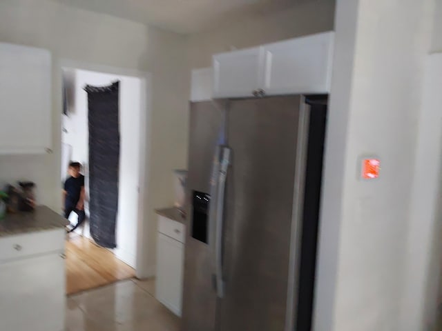 kitchen with stainless steel refrigerator with ice dispenser, light hardwood / wood-style flooring, and white cabinetry