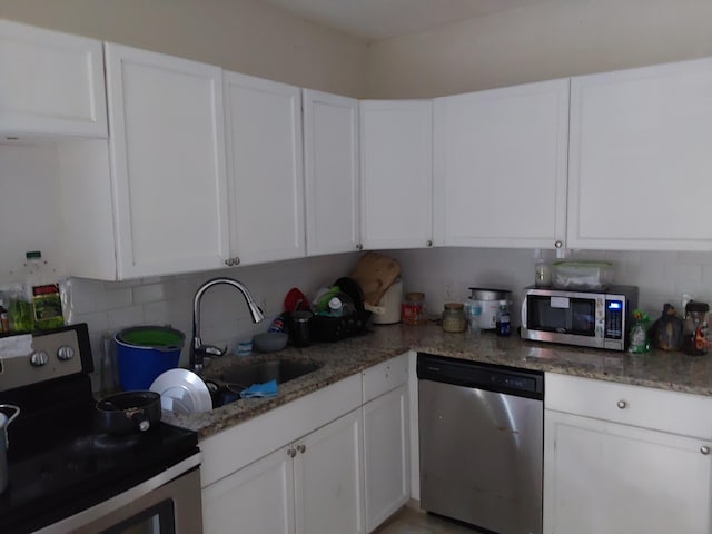 kitchen with light stone counters, stainless steel appliances, sink, and white cabinets