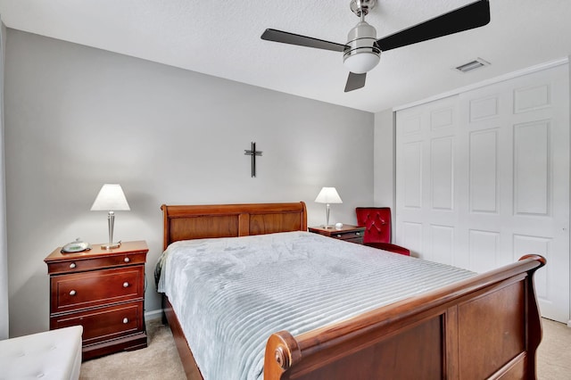 bedroom with a closet, a textured ceiling, light colored carpet, and ceiling fan