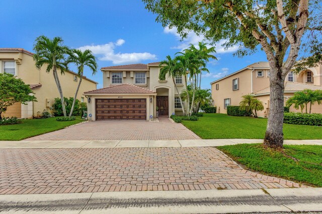 8951 Alexandra Cir, Wellington, FL 33414 - mediterranean / spanish house featuring stucco siding, a garage, decorative driveway, a front yard, and a tiled roof