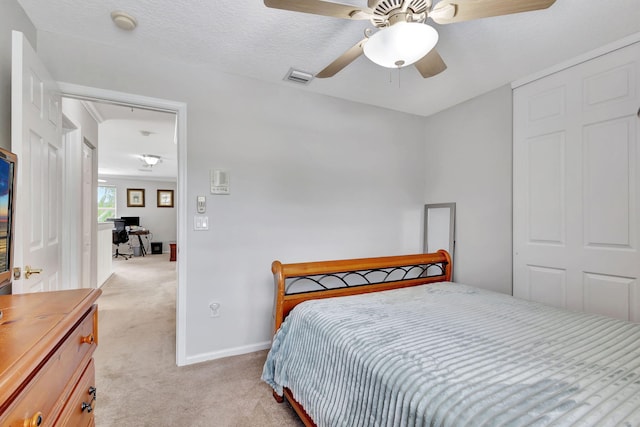 carpeted bedroom with ceiling fan and a textured ceiling