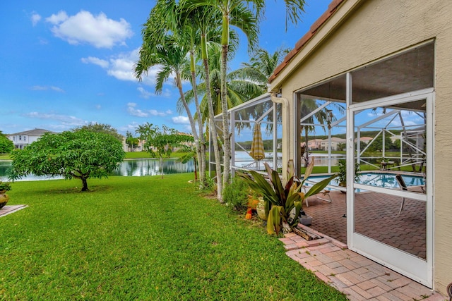 view of yard with a water view, a patio, and glass enclosure