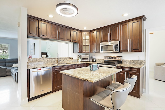 kitchen with dark brown cabinetry, stainless steel appliances, sink, and a breakfast bar area