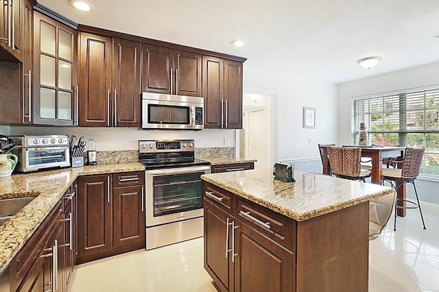 kitchen with dark brown cabinetry, light tile patterned flooring, and stainless steel appliances