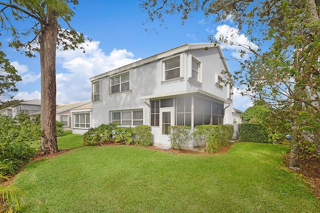 rear view of property featuring a sunroom and a lawn