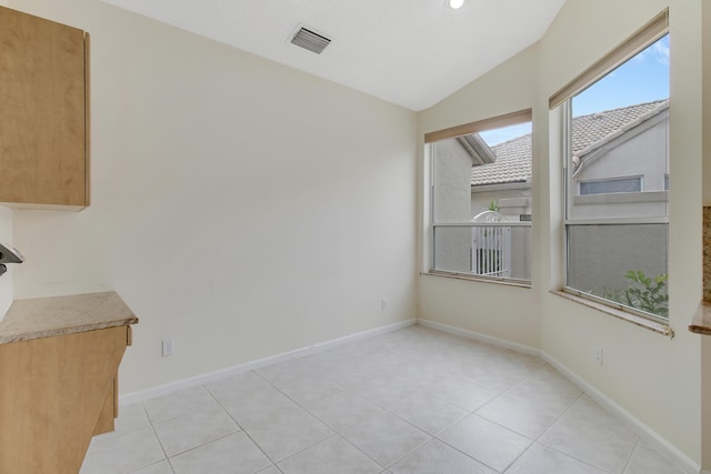 unfurnished dining area with lofted ceiling and light tile patterned floors