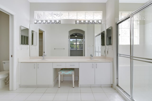 bathroom with ceiling fan, vanity, toilet, and an enclosed shower