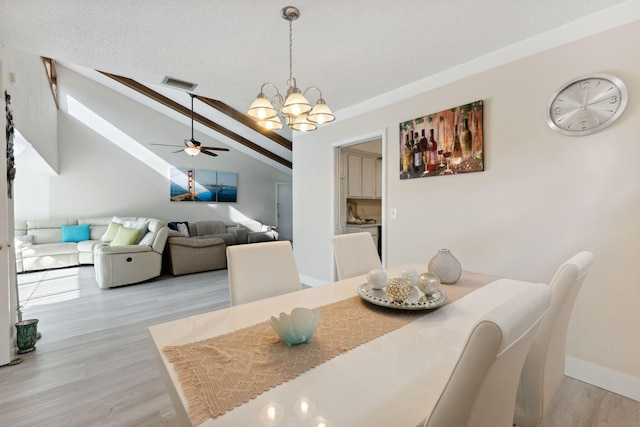 dining area featuring vaulted ceiling with beams, light wood-type flooring, and ceiling fan with notable chandelier