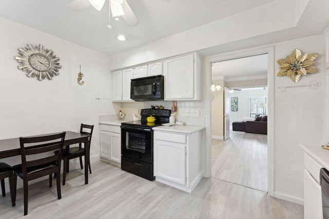 kitchen with light hardwood / wood-style floors, black appliances, and white cabinets