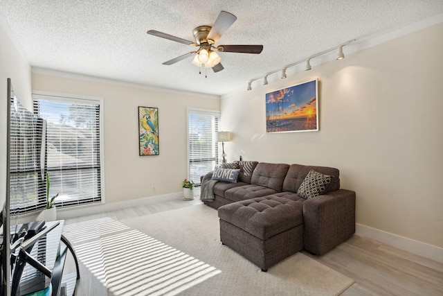 living room featuring a textured ceiling, light wood-type flooring, plenty of natural light, and ceiling fan