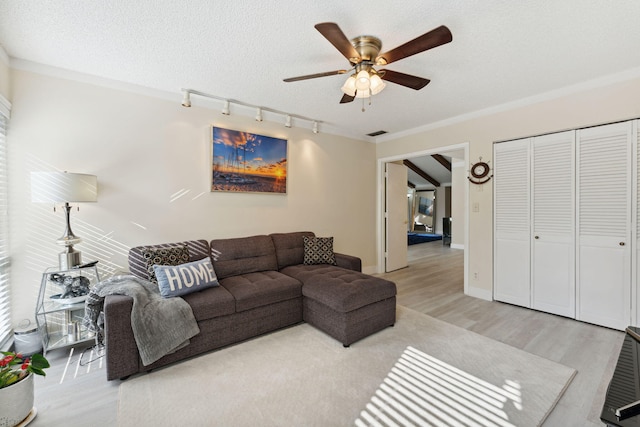 living room with a textured ceiling, light wood-type flooring, and ceiling fan