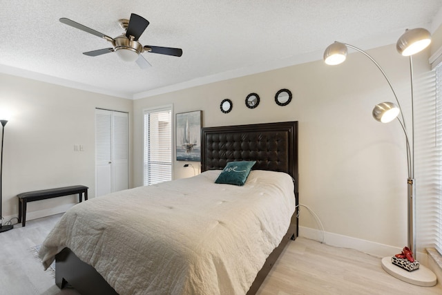 bedroom with a closet, a textured ceiling, light wood-type flooring, and ceiling fan