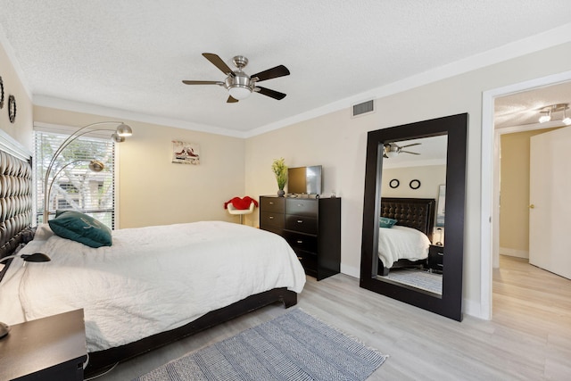 bedroom featuring ceiling fan, crown molding, a textured ceiling, and light hardwood / wood-style floors