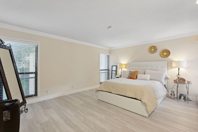 bedroom with light hardwood / wood-style floors, a textured ceiling, and ornamental molding