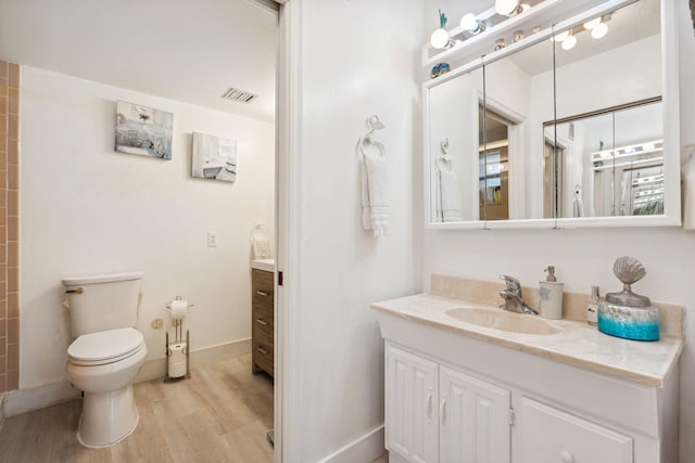 bathroom with toilet, vanity, and wood-type flooring