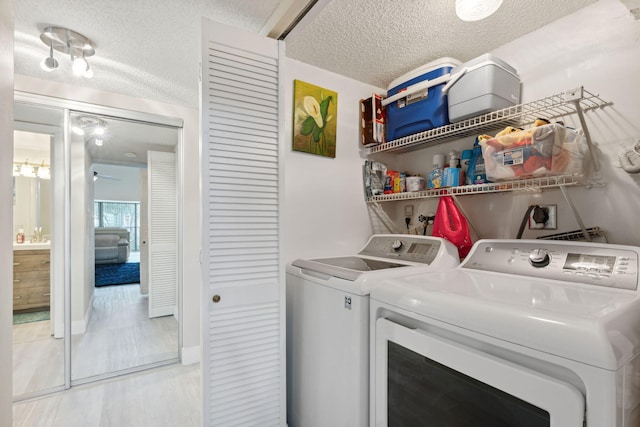 laundry area featuring light hardwood / wood-style flooring, a textured ceiling, and washing machine and dryer