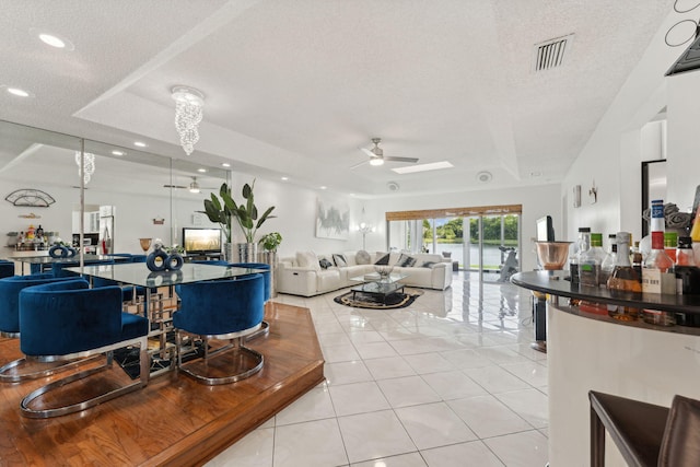 tiled living room with a textured ceiling and ceiling fan with notable chandelier