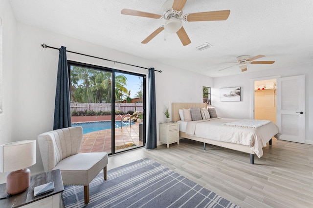 bedroom with access to outside, a textured ceiling, light wood-type flooring, and ceiling fan