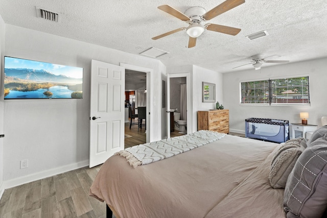 bedroom with ceiling fan, wood-type flooring, a textured ceiling, and ensuite bathroom