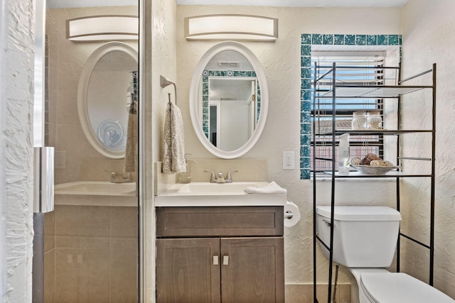 bathroom with toilet, vanity, and tiled shower